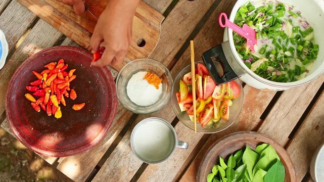 Person preparing spicy indonesian sambal matah on a wooden table
