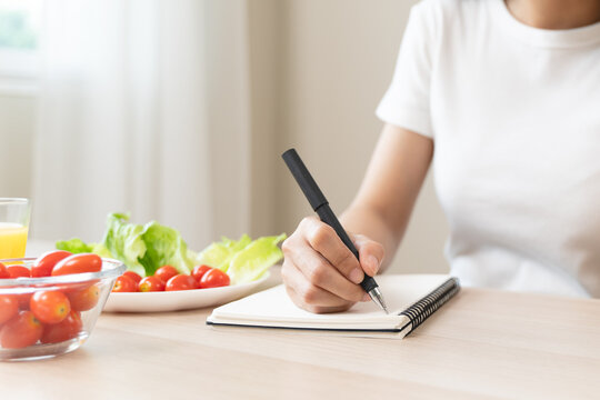 Wellbeing of health with good food control concept. Woman writing the meal note and plan to eat during diet program to loss weight goal for balance nutrition and calories.