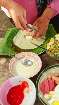 Indonesian woman making traditional spring rolls outdoors