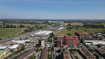 Fototapeta premium Aerial View of Urban Sprawl: An expansive aerial photograph captures the intricate network of a developing town, showcasing residential buildings, industrial zones. Mombretto, Milano, Italia