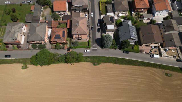 Aerial View of Suburban Street: An aerial perspective reveals a quiet suburban street lined with houses and bordered by a vast agricultural field, Mombretto, Milano, Italia