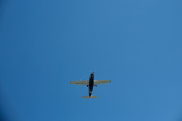 Fototapeta premium Low Angle View of a Single-Propeller Plane Flying in Clear Blue Sky