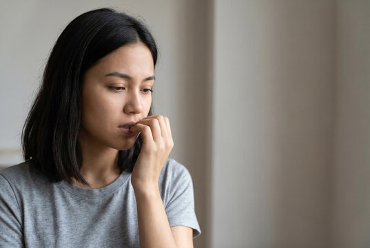 Young woman biting nails due to worry, anxiety, and mental stress