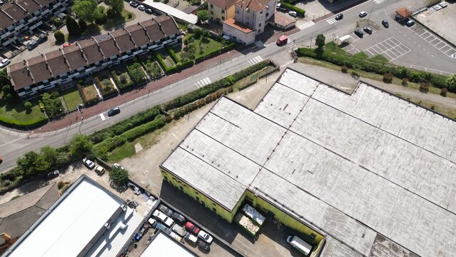 Urban Industrial Aerial View: An aerial perspective captures a bustling urban landscape featuring industrial buildings, residential townhouses, and a street with light traffic.
