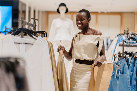 Focused Black Female Customer Choosing Trendy Outfit in Retail Store