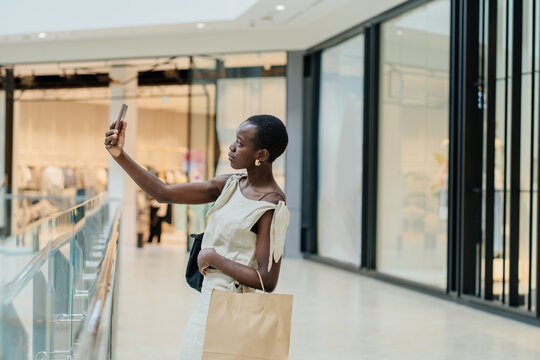 Modern Black Influencer Capturing Content with Smartphone in Fashion Mall