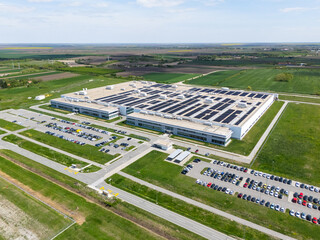 Naklejka premium Aerial view of a modern factory with solar panels and energy storages on the roof