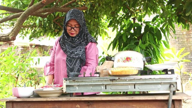 Muslim woman preparing traditional Indonesian crepes outdoors
