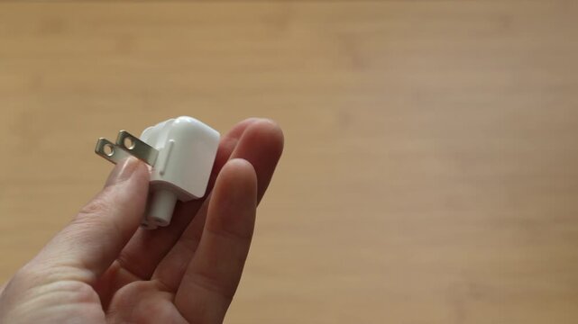 Close up of male hands holding American and European power plugs. Concept of electricity standards, travel adapter, device compatibility and connection types.