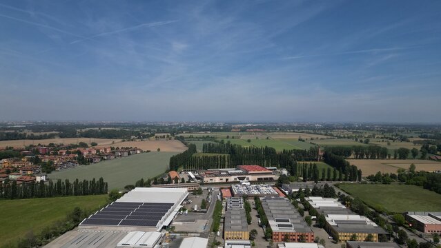 Urban Harmony: An aerial view showcases the convergence of an industrial zone and agricultural lands, blending urban and rural landscapes under a serene sky. 