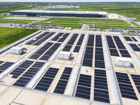Aerial view of a modern factory with solar panels and energy storages on the roof
