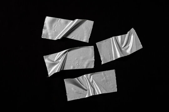 Set of silver adhesive cloth tape strips. Concept for repair, fixing, industrial tools, and textured graphic elements on black background.