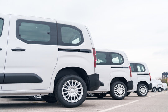 White delivery vans are parked in rows. Commercial fleet of vehicles