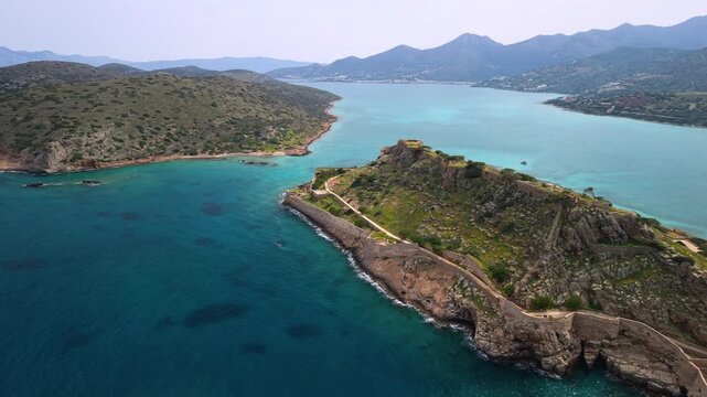 Spinalonga Island Crete Greece aerial view of Venetian fortress and Kalydon Peninsula, Elounda bay panoramic drone flight with mountains, Mirabello Gulf coastal landscape on Greek islands