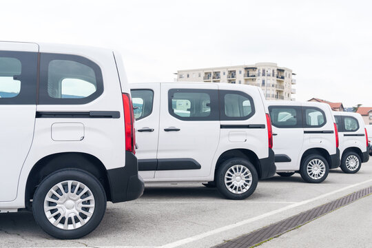 White delivery vans are parked in rows. Commercial fleet of vehicles