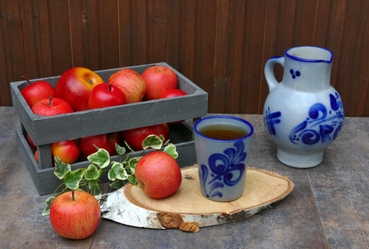 Hessischer Apfelwein im Bembel  mit frischen roten &Auml;pfeln in einer Holzkiste.