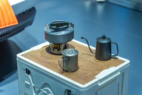 Picnic with teapot,suitcase and camp chairs beside car open door