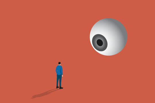 Businessman standing under a giant floating eyeball, representing corporate surveillance, oversight, and public scrutiny
