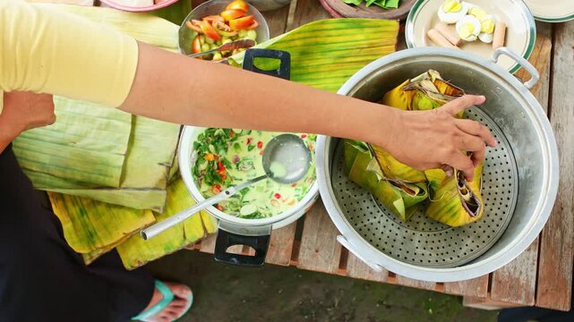 People preparing traditional indonesian food in banana leaves