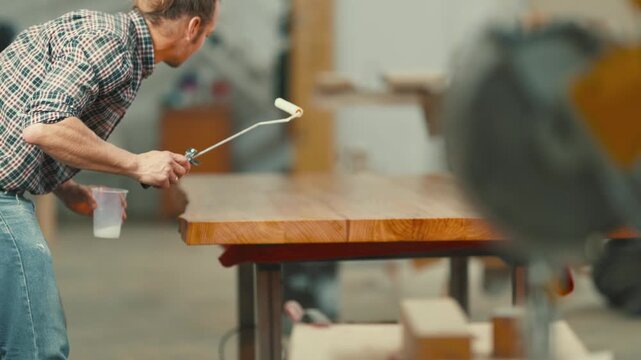 Carpenter applying varnish on a wooden tabletop