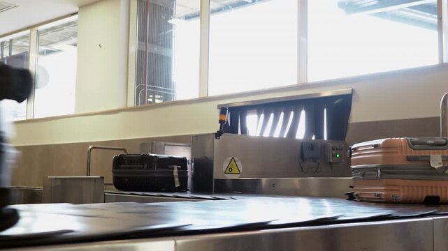 A large suitcase travels along the airport baggage carousel belt captured in motion blur, conveying the flow of passenger luggage after arrival