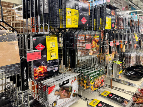 Barnaul, Russia, 06.06.2025: BBQ grill baskets and grilling accessories on retail store shelves. Forester and ECOS brand barbecue tools displayed for sale in a hardware supermarket.