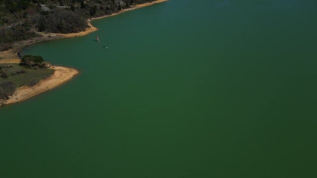 Alone windsurfing on a green lake in France