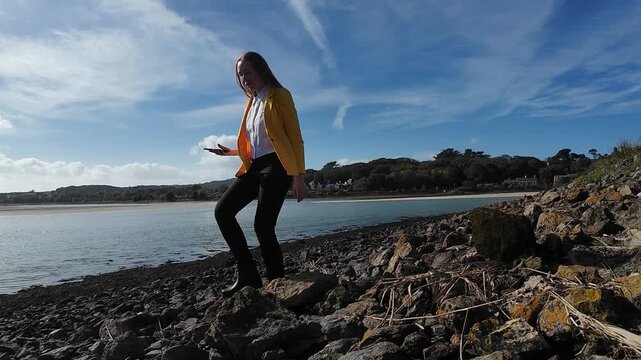 A woman walks on the evening seaside wearing yellow jacket