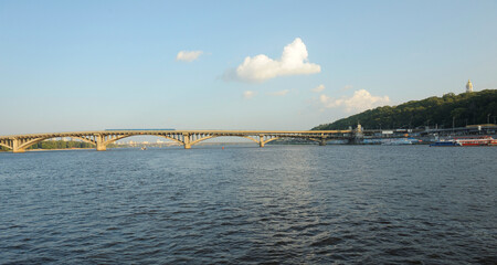 Obraz premium Metro bridge with blue subway trains over Dnieper river in Kyiv Ukraine, sunny summer city landscape