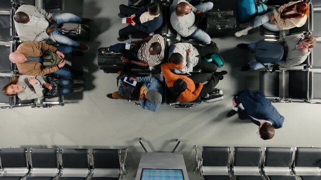 Checking departure board, timetable and busy airport terminal filled with people, top down view. Catching plane for holiday trips, FIDS screen schedule and diverse travelers high angle shot
