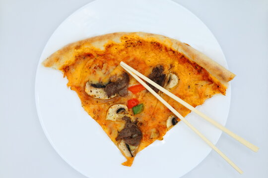 Eat pizza with wooden chopsticks. No cutlery. Concept food joke.
