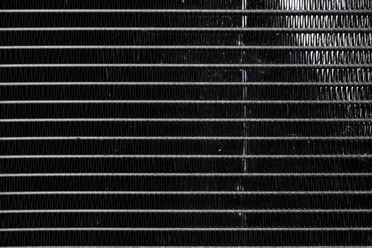 Detailed background of black aluminum radiator cooling fins. Ideal for automotive industry, mechanical engineering, and industrial textures.