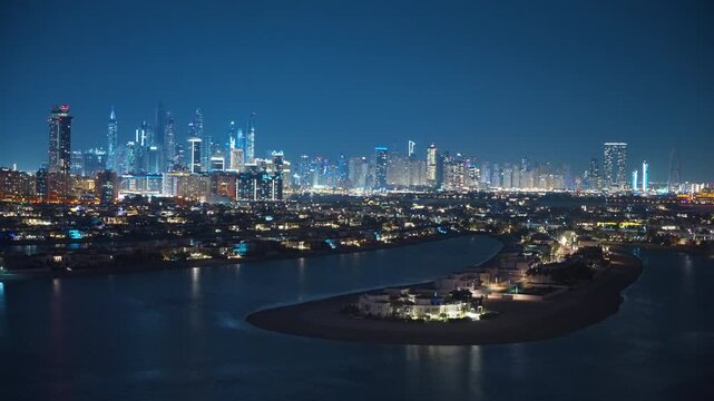 Stunning aerial view of Dubai Marina skyline at night with illuminated skyscrapers reflecting on calm waters, luxury Palm Jumeirah villas in foreground, deep blue twilight sky creating urban elegance.