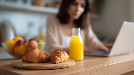 Fototapeta premium Woman enjoy breakfast with fresh croissants and orange juice work on laptop computer at home, focus on healthy food, remote office concept