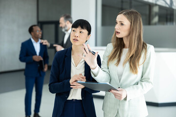 Fototapeta premium Diverse businesswomen discussing strategy and ideas during a meeting, working together in a professional corporate environment