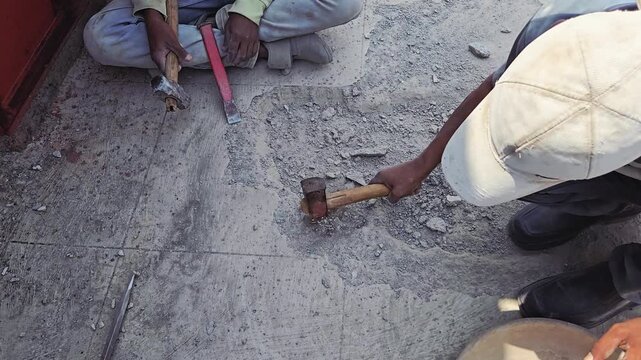 An artisan skillfully breaks a slab using a hammer & chisel. This manual technique is vital for waterproofing & repair, showcases the precise labor required in construction & stone production. No face