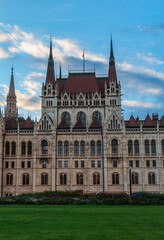 Fototapeta premium Magnificent Hungarian Parliament Building in Budapest under a beautiful blue sky with clouds during sunset featuring neo-gothic architecture and famous landmark details