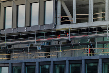 Naklejka premium Construction workers build a new office building in a busy urban area during daytime hours