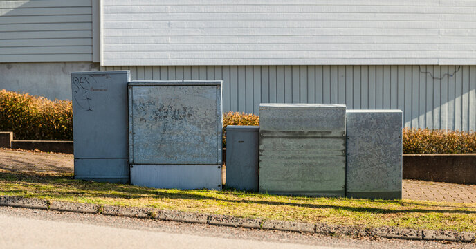 Street side electrical utility cabinets installed along residential neighborhood sidewalk.