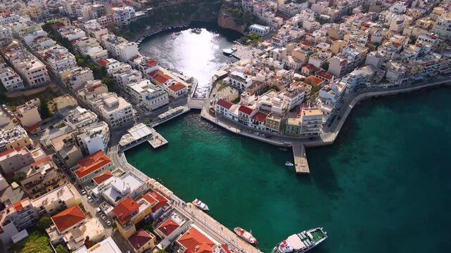 Agios Nikolaos Crete Greece 4k aerial drone top down view marina over Voulismeni lake. Scenic panorama of coastal city with turquoise bays jagged coastline and luxury yachts. Greek travel landmarks