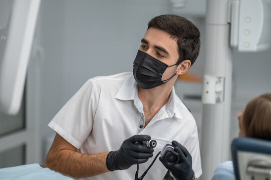 Doctor holding intraoral camera inspecting oral cavity