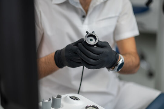 Doctor in black gloves holding endoscopy lens