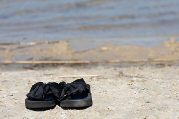 czarne klapki na plaży na tle wody © workszop