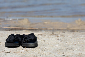 czarne klapki na plaży na tle wody © workszop