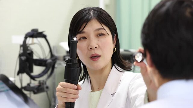 ペンライトで目の状態を診察する眼科医と男性患者の診療シーン