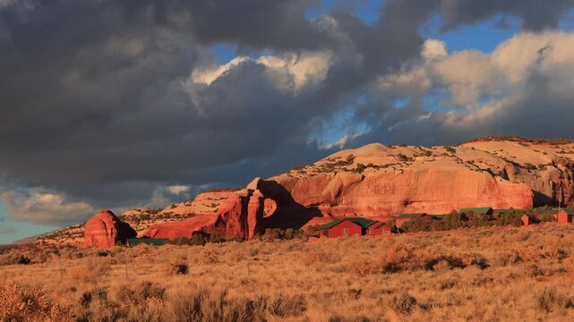 Red rock formations with cabins under dramatic clouds.