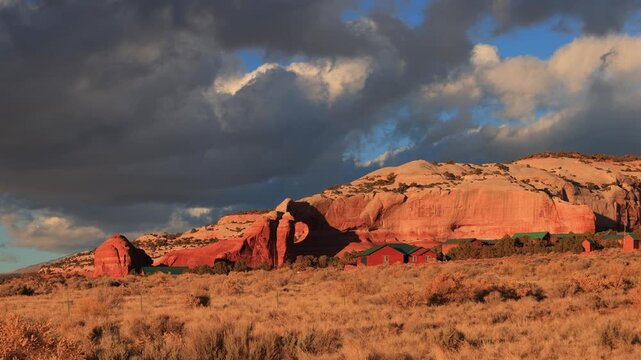 Red rock formations with cabins under dramatic clouds.