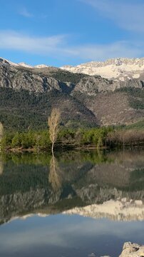 Cinematic pan of a tranquil mountain reservoir with a moored boat