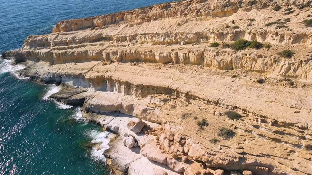 Greece Crete Matala Beach 4K Drone Aerial Video of Sandstone Caves at Golden Hour Revealing Hippie Caves Scenic Coastline and Blue Sea Travel Destination