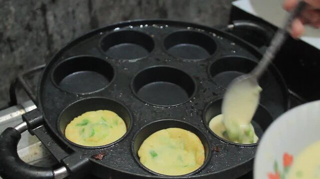 Cooking mini omelets with green onions in a traditional round mold pan